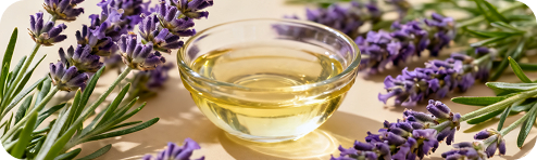 Lavender sprigs beside a small bowl of pale oil